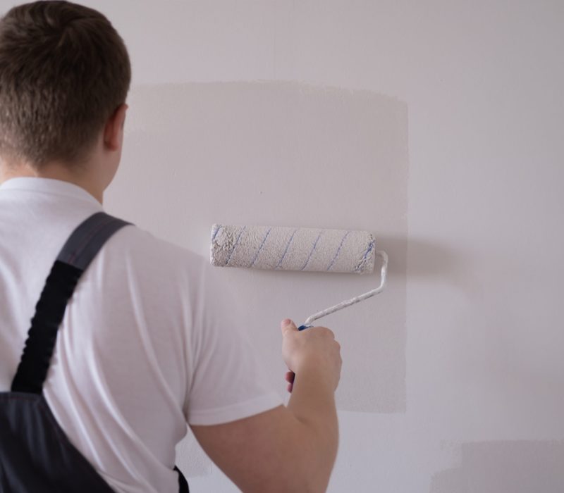 Home renovation works and tips. Male painting a wall with white color.